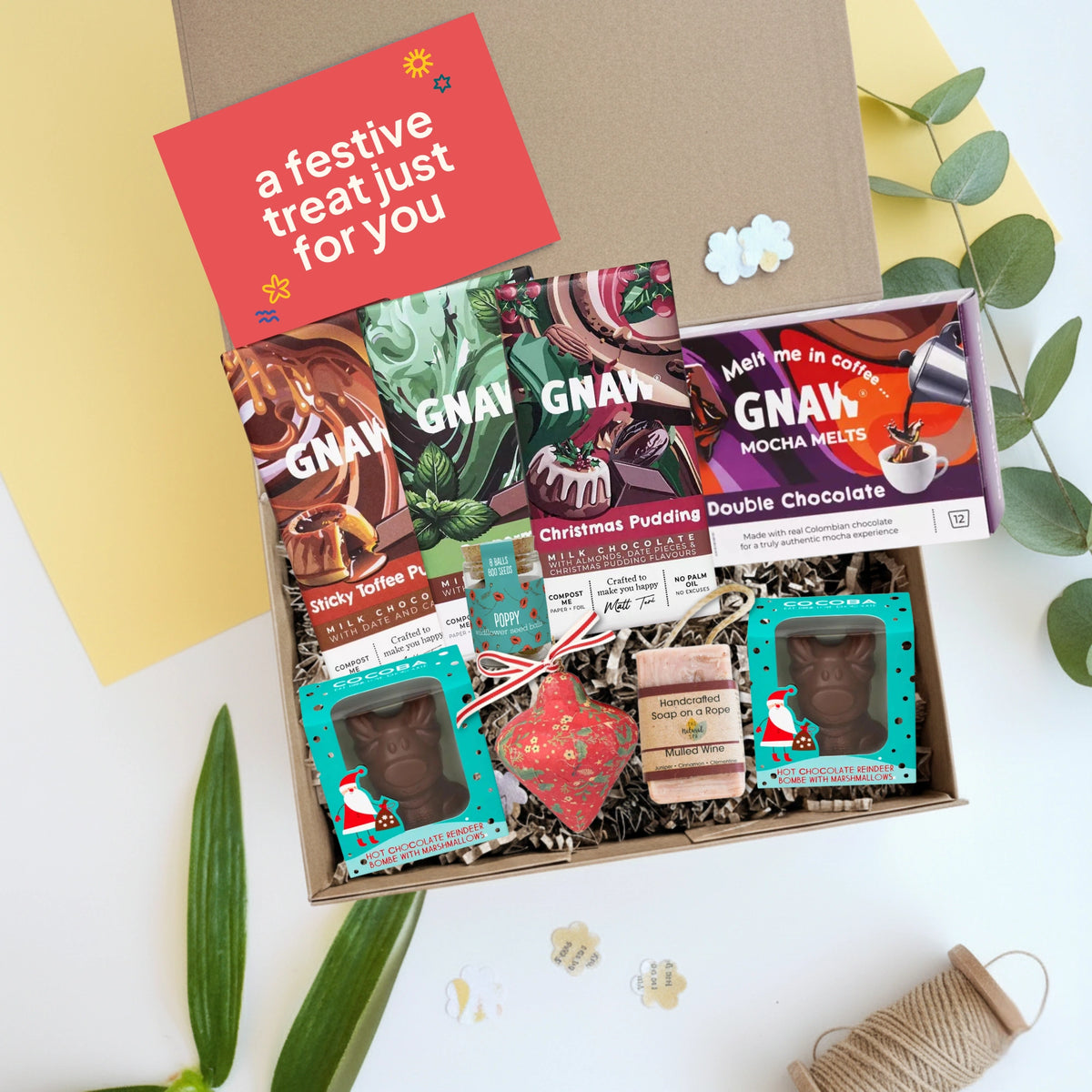 Box of GNAW chocolate treats with a handmade Christmas decoration, wildflower seedballs and a festive soap bar  on a white background