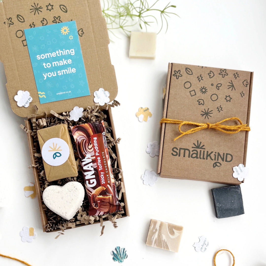 Smallkind deluxe hug in a box gift with luxury chocolate bar, heart shaped bath bomb and small wrapped natural soap bar inside a hand stamped kraft gift box on a white background.