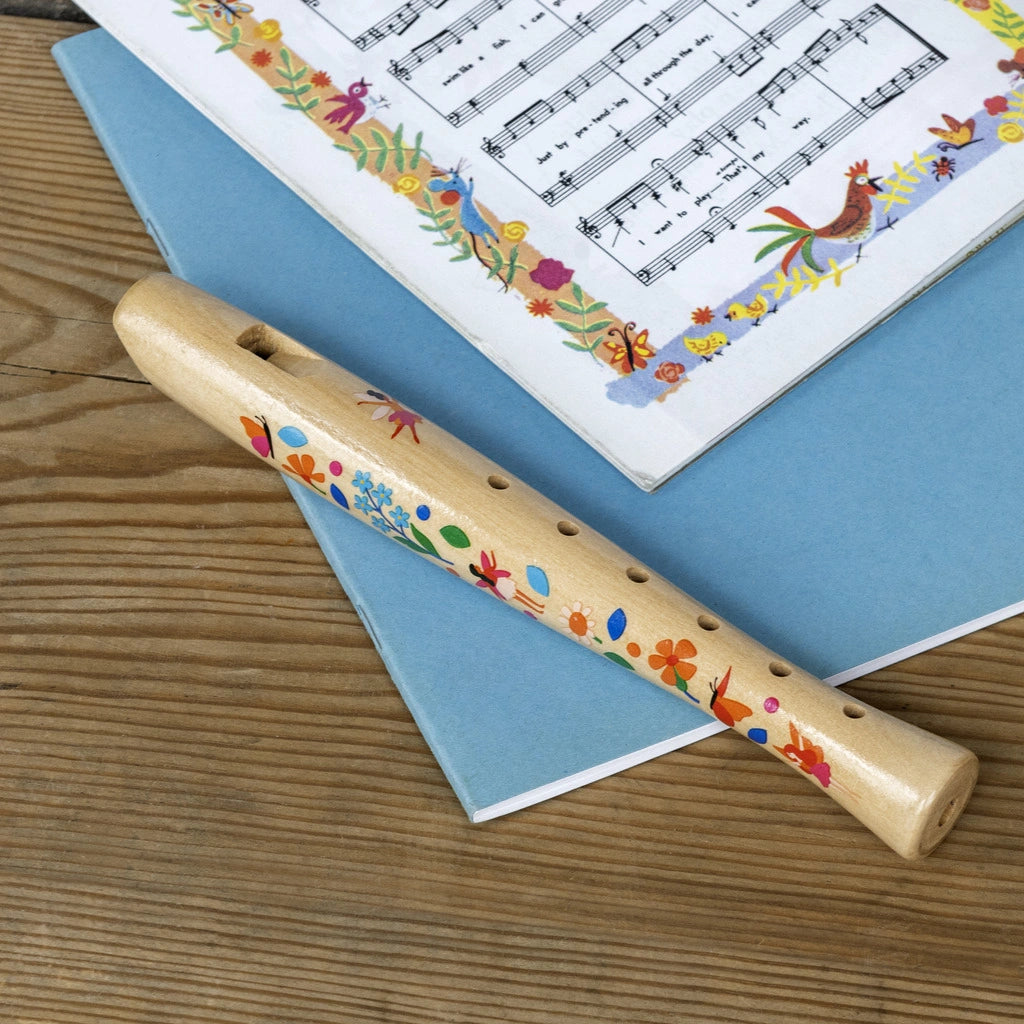 wooden recorder for children laid on a table with musical sheets. 