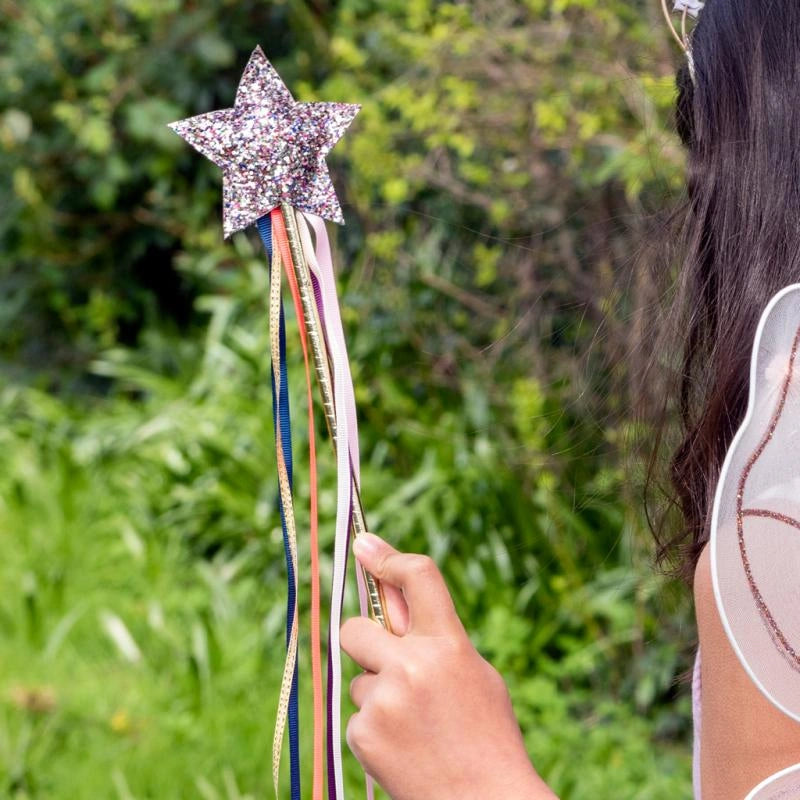 girl in a garden holding a glitter Star Wand with colourful ribbons. The wand is suitable fro children aged 3 and over. 