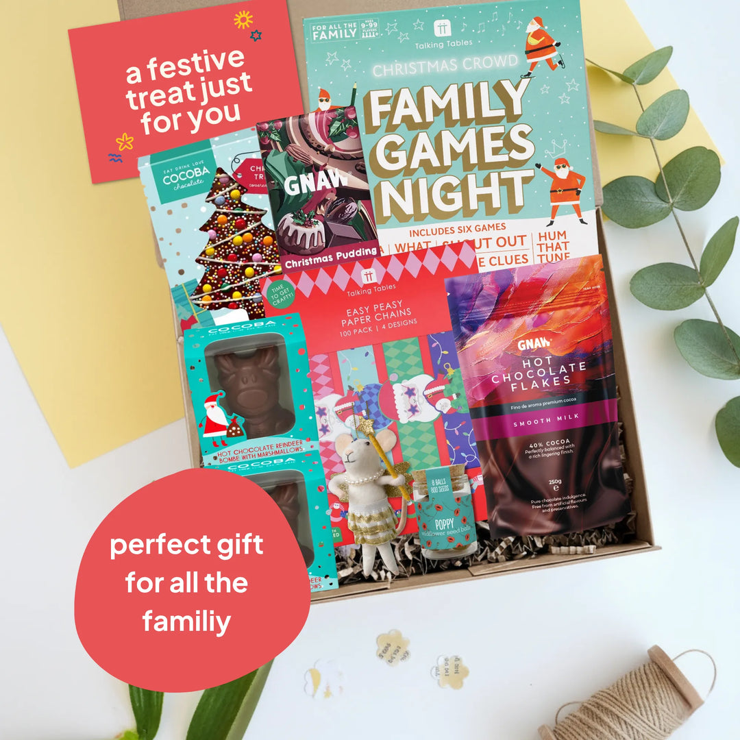 A Christmas-themed family gift set arranged in a box on a white surface with decorative leaves and paper. The set includes &