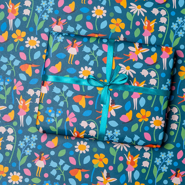 a gift wrapped in colourful fairy and floral pattern wrapping paper with blue ribbon on matching background