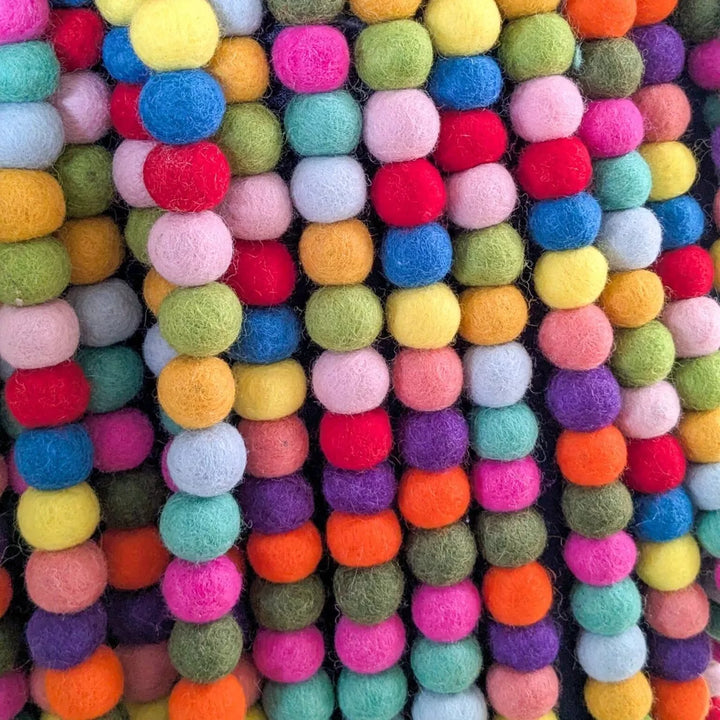 Multicolored felt ball garland on a black background