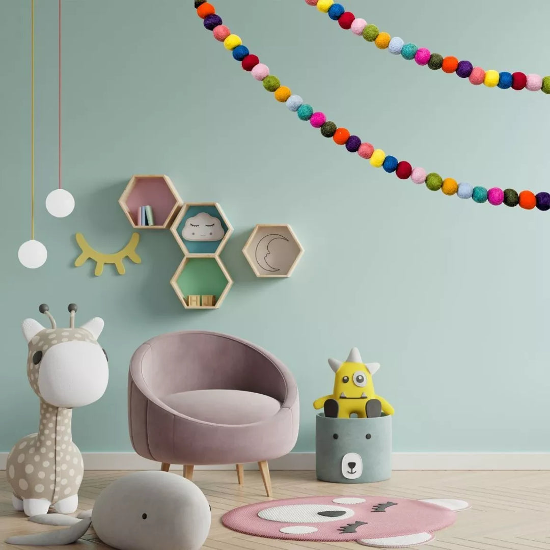 Children's room with a pink chair, colorful decorations, and toys on a light green wall.
