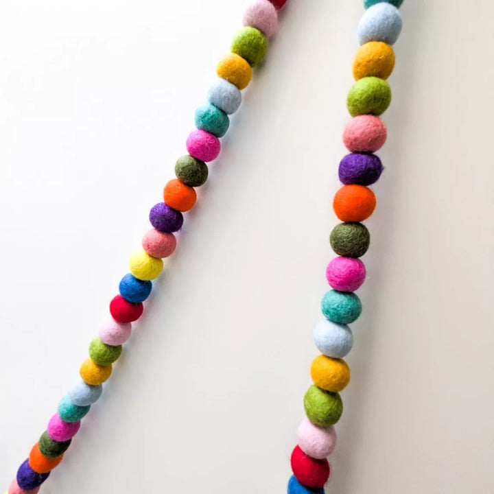 Colourful felt ball garland on a white background