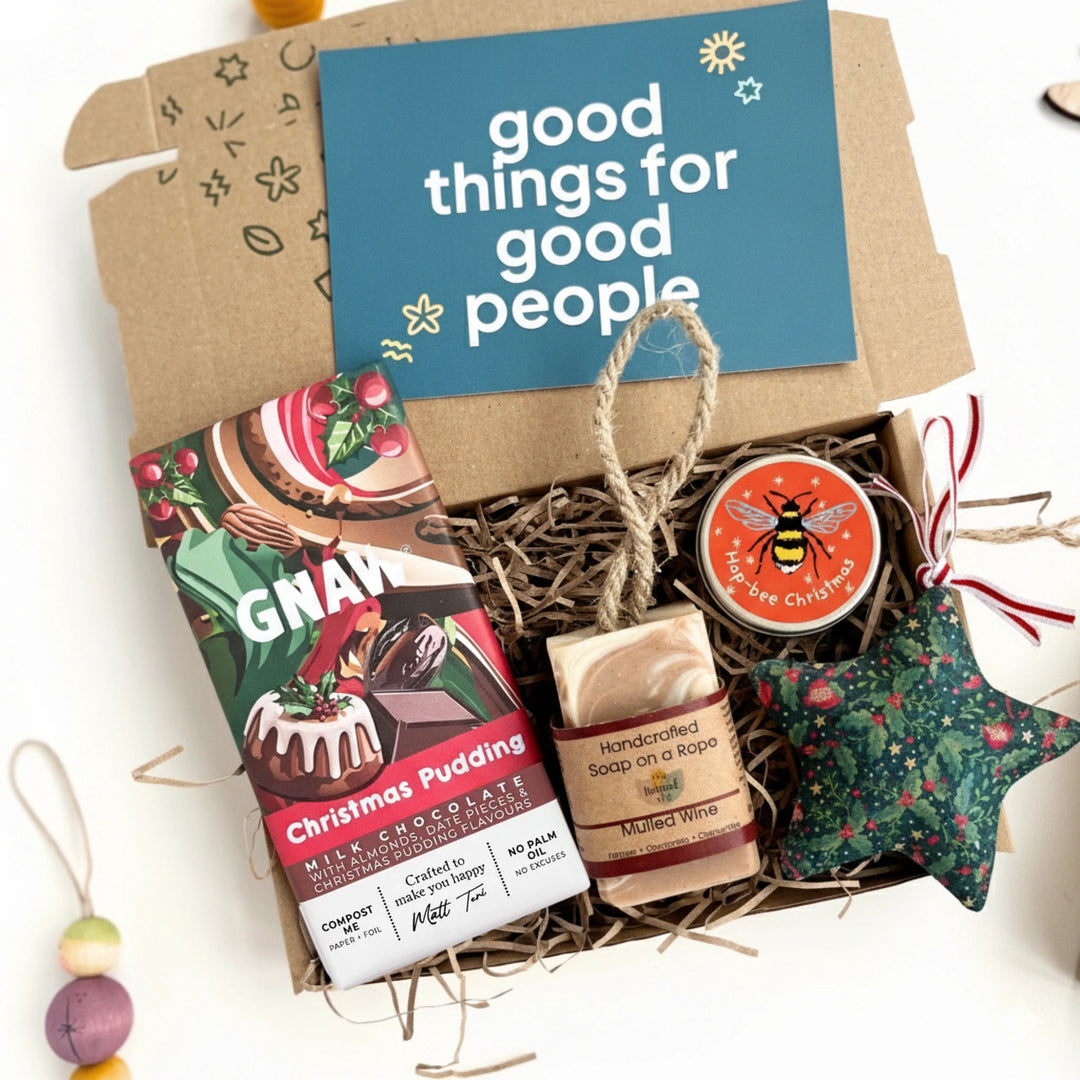 Gift basket with Christmas pudding chocolate bar, soap, and green star-shaped christmas decoration, featuring a 'good things for good people' card.