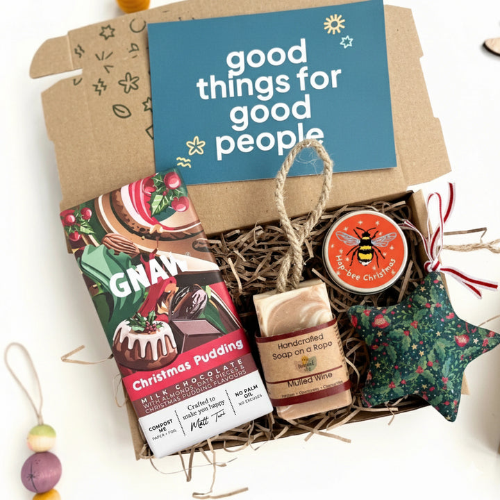 Gift basket with Christmas pudding chocolate bar, soap, and green star-shaped christmas decoration, featuring a 'good things for good people' card.