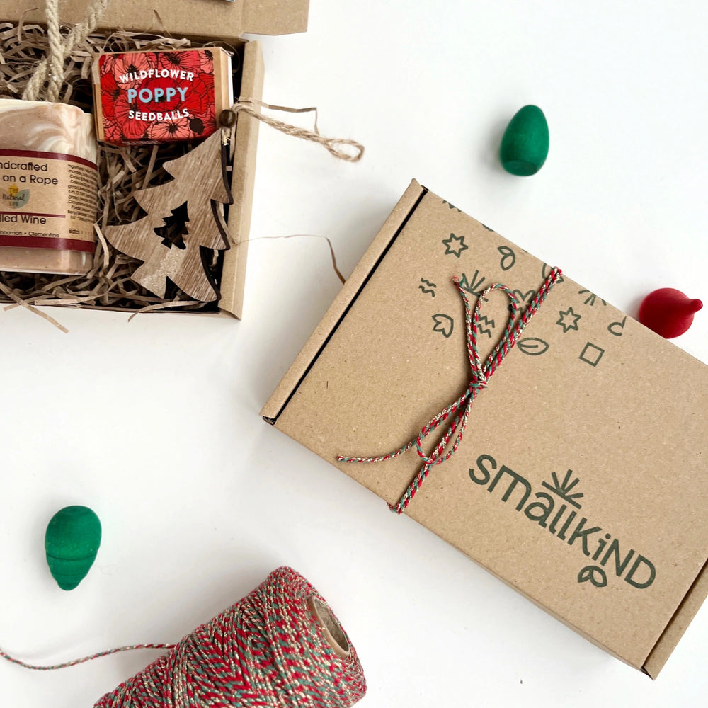 Hand stamped kraft gift box with a green pattern and smallkind logo. The box is tied with red glitter twine. 