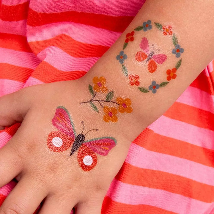 little girls arm with three flower and butterflies temporary tattoos. 