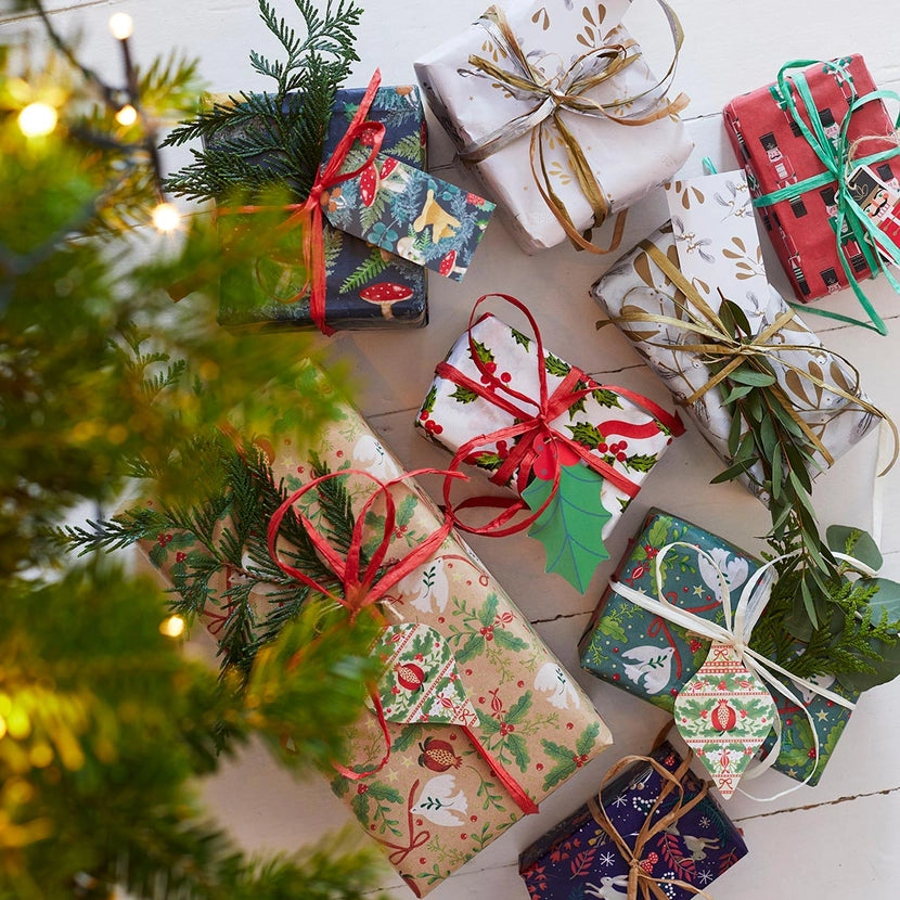 Colourful Christmas presents under a decorated tree with raffia twine and paper eco christmas gift tags.