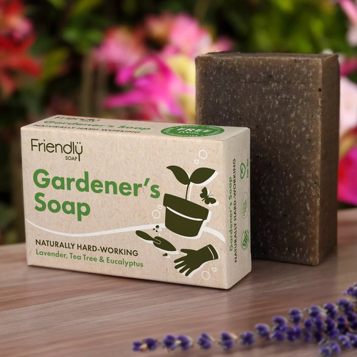 Gardeners' Soap packaging with a bar of soap on a wooden surface with flowers in the background