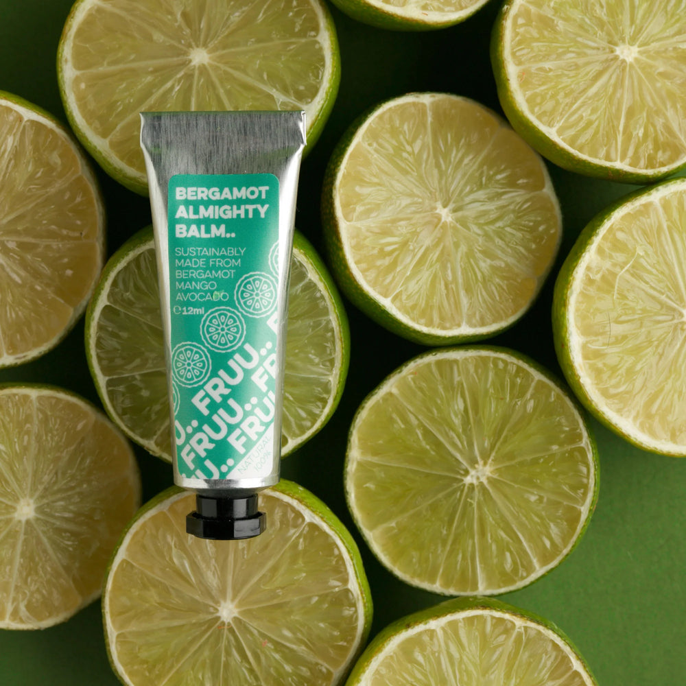 fruu costmetics Bergamot Almighty Balm for dry skin. the balm is in an aluminium tube and is lying on some fresh slices limes