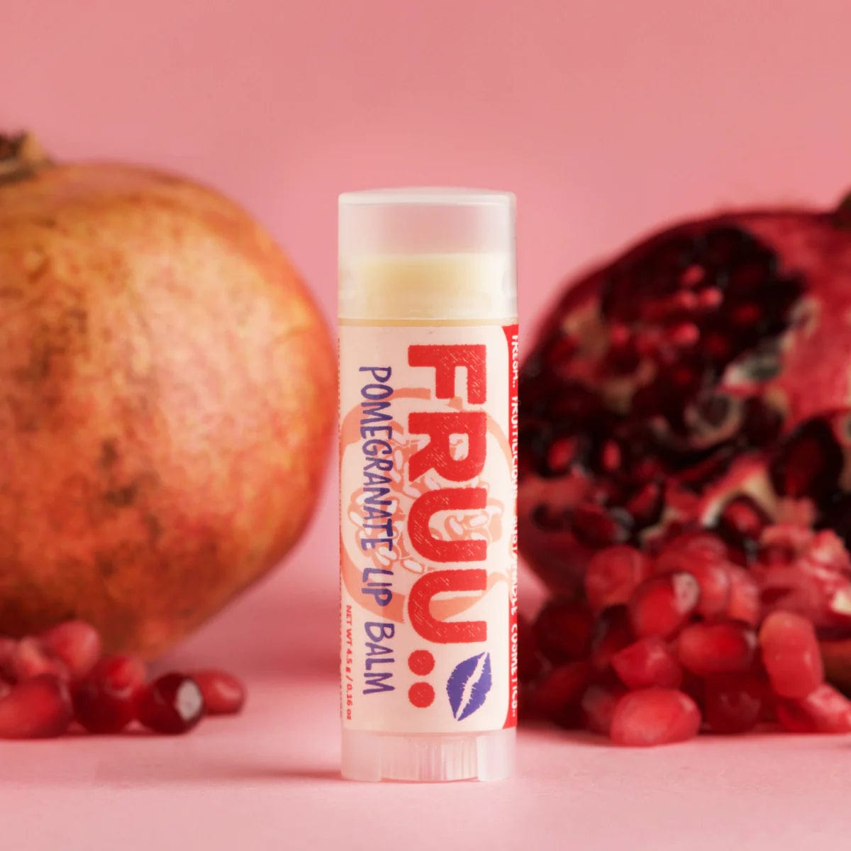 FRUU Pomegranate Lip Balm in a plastic tube with a pomegranate in the background