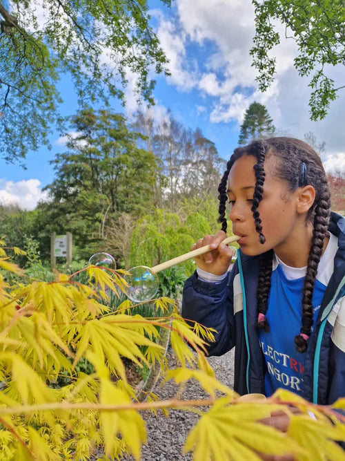 girl blowing bubbles with the Dr Zigs Bubble Pollinator Kit