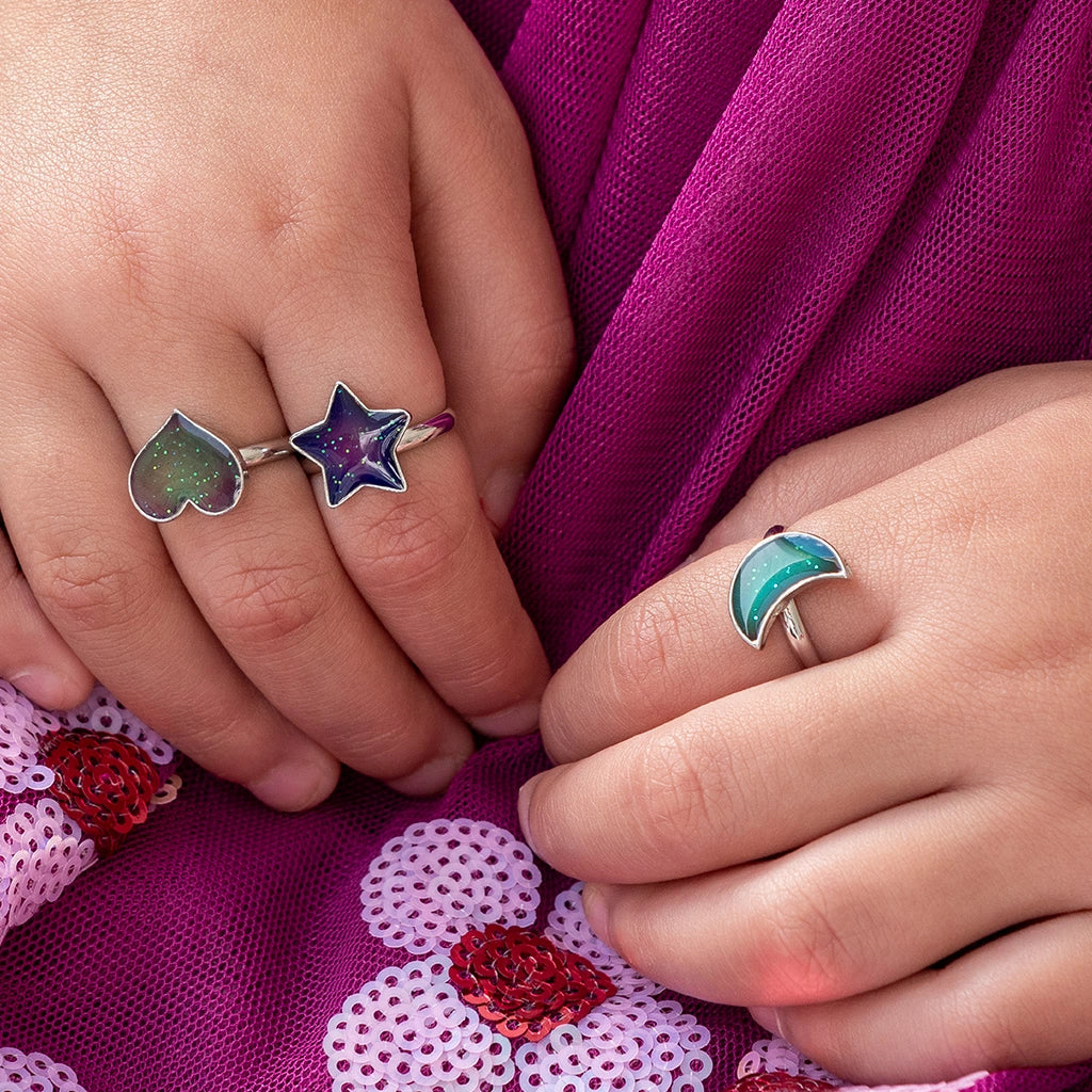 child wearing three children's silver mood rings in star, heart and moon shapes.