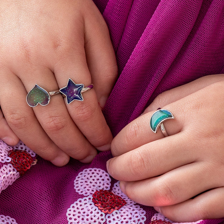 child wearing three children's silver mood rings in star, heart and moon shapes.