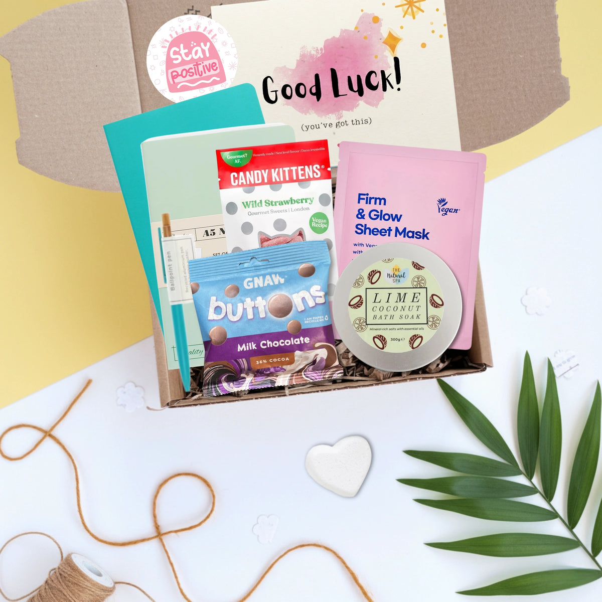 Assorted products including a sheet mask, candy, and chocolate in a box with good luck card on a decorative background.