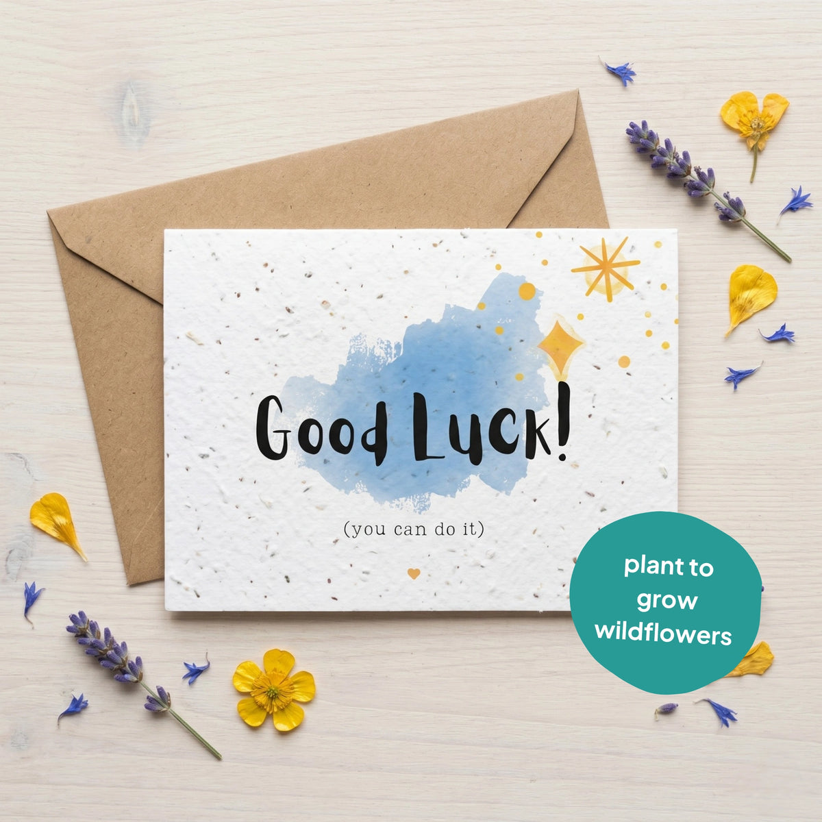Good Luck card with plantable seeds, envelope, and decorative flowers on a light background