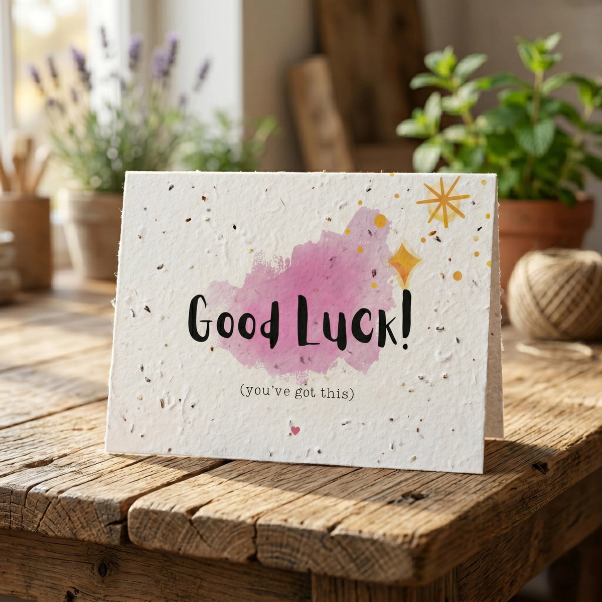Good Luck card with watercolour design on a wooden surface with plants in the background