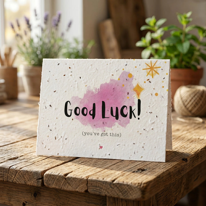 Good Luck card with watercolour design on a wooden surface with plants in the background