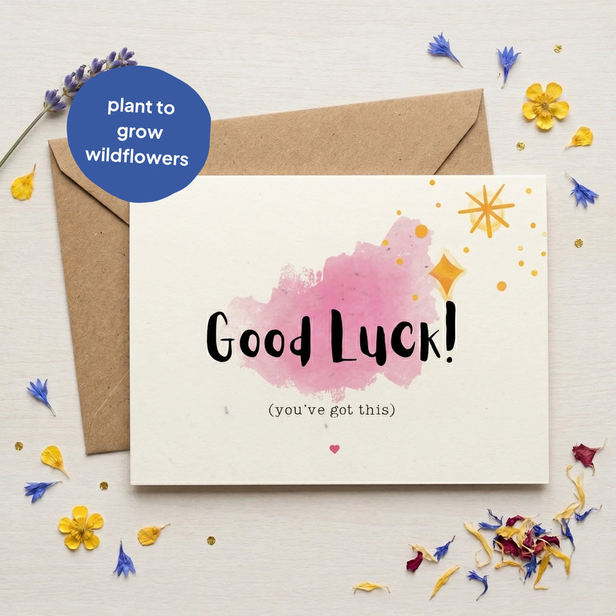 Good Luck card with pink watercolour design and text, surrounded by small flowers on a light background.