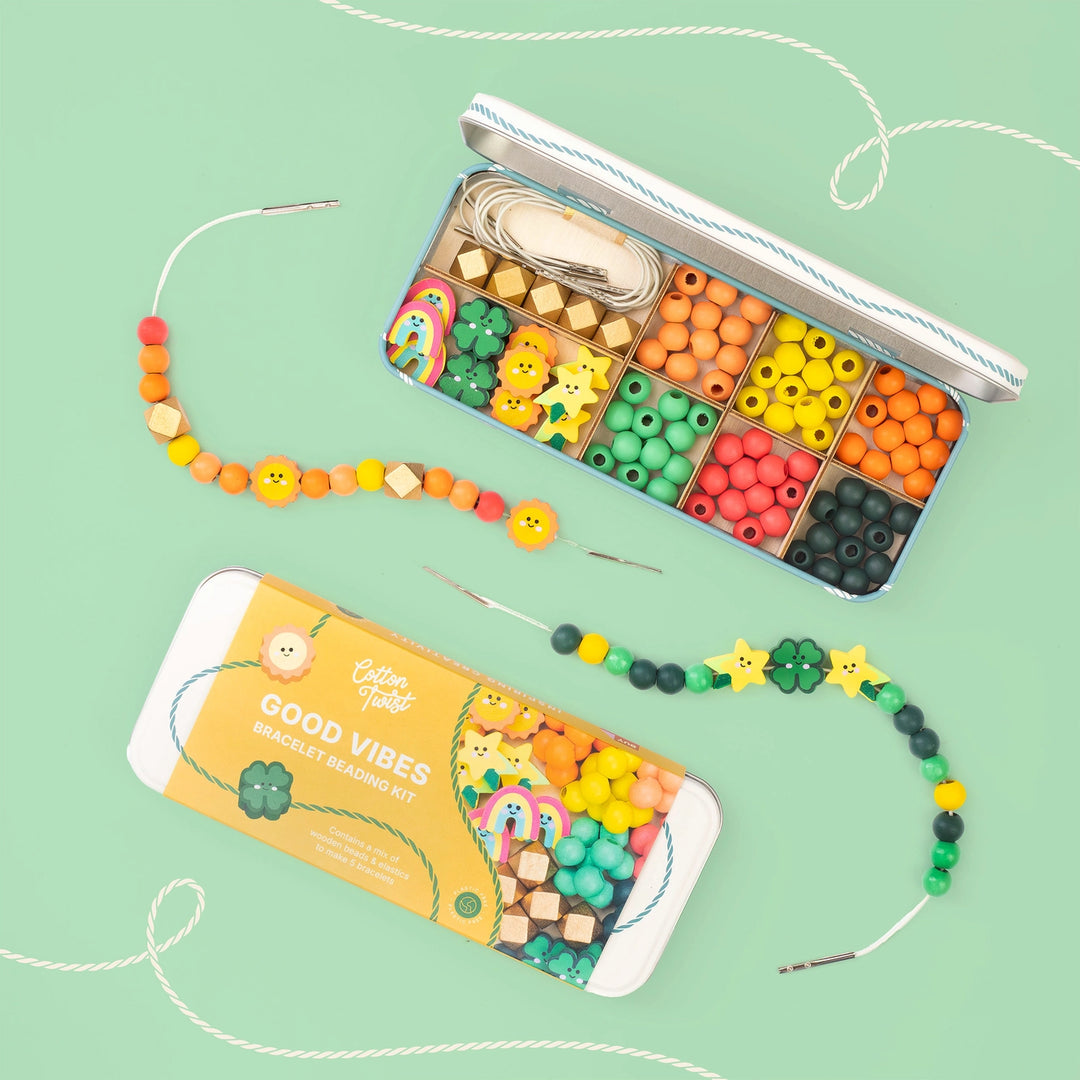 Colourful bead kit with beads and tools on a green background
