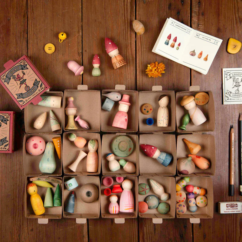 Collection of small wooden toys from Grapat Lucky Lucky 4th edition boxes on a wooden surface with a card displaying illustrations.
