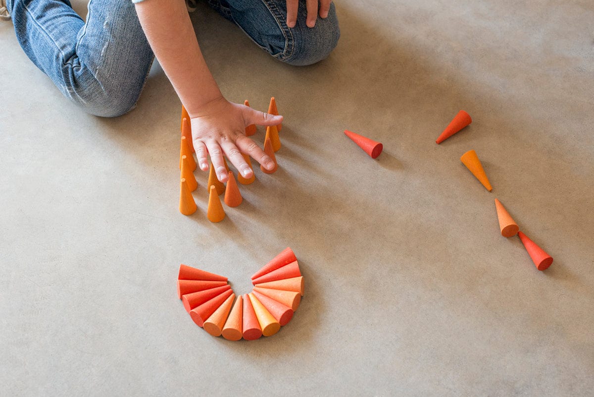 child playing with orange cones loose parts on a neutral carpet 