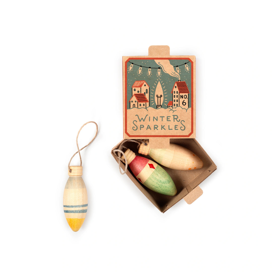 Wooden Christmas ornaments in a decorative box labeled 'Winter Sparkles' on a white background