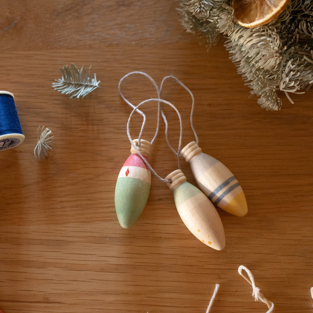 Wooden lamp shaped christmas decorations on a wooden surface with decorative elements