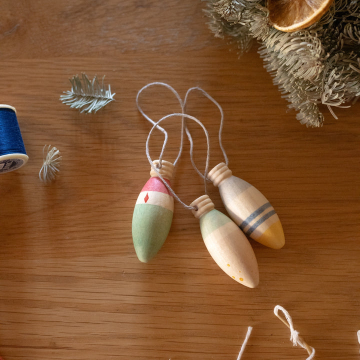 Wooden lamp shaped christmas decorations on a wooden surface with decorative elements