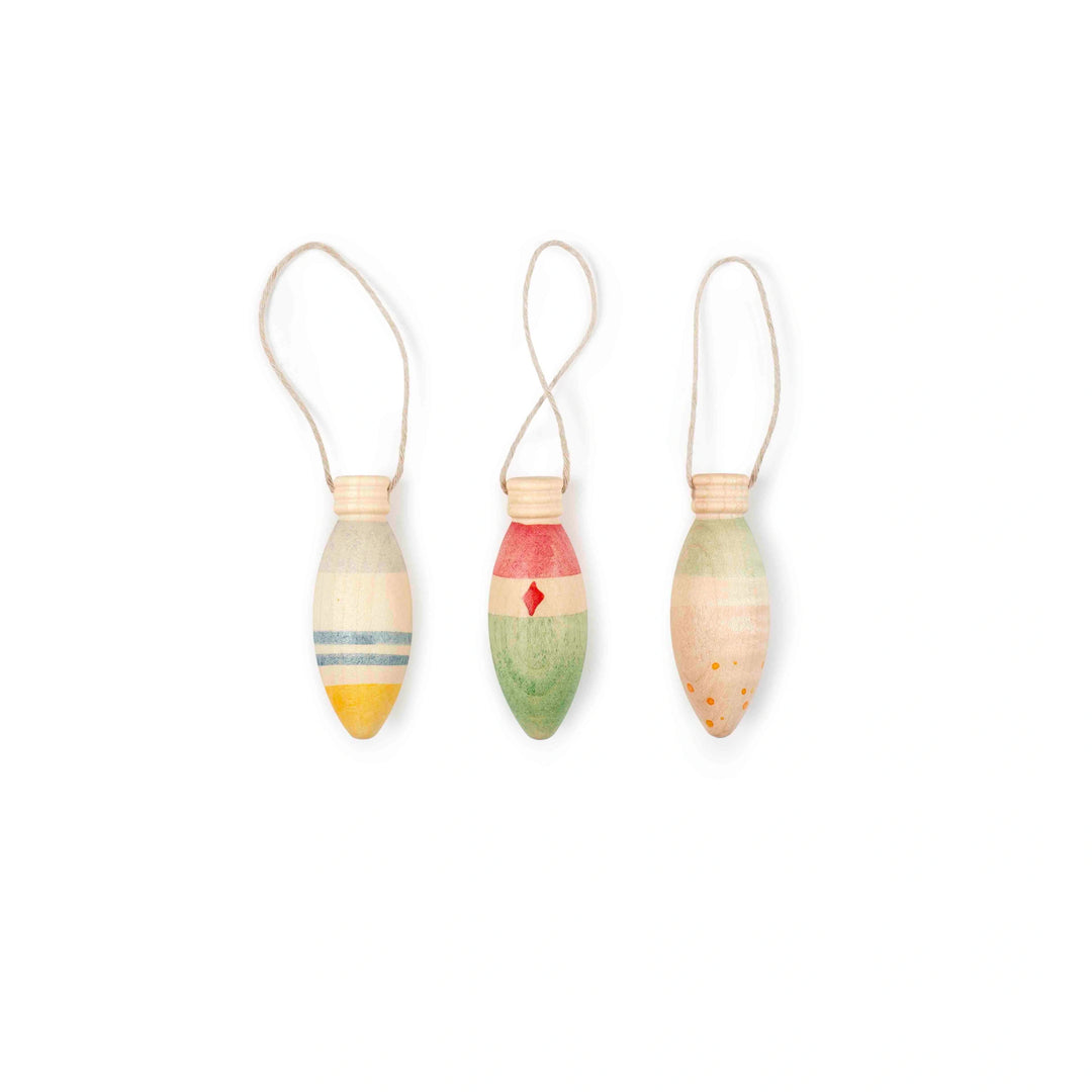 Three colourful painted wooden christmas tree decorations shaped like bulbs on a white background