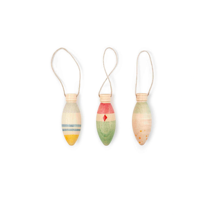 Three colourful painted wooden christmas tree decorations shaped like bulbs on a white background