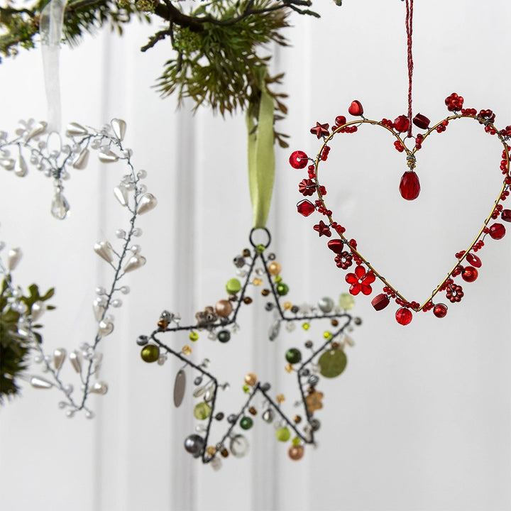 three handmade beaded decorations - white heart, red heart and green star hanging on a christmas tree.