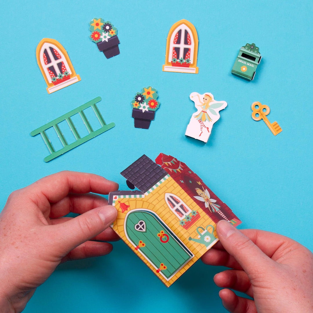 Colorful miniature fairy house model with decorative elements on a blue background