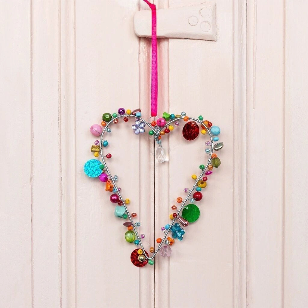 beaded heart decoration hanging on a pink wall 