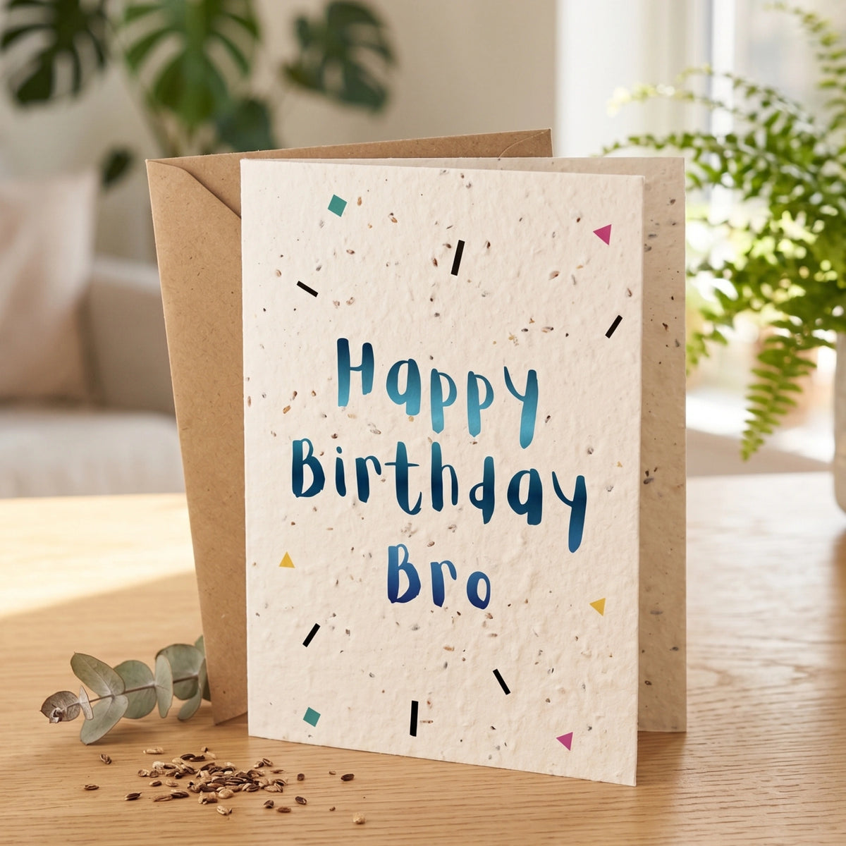 Birthday card with 'Happy Birthday Bro' text on a wooden surface with plants in the background