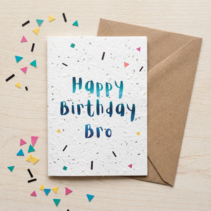 Birthday card for 'Bro' with colourful confetti and a brown envelope on a light wood background