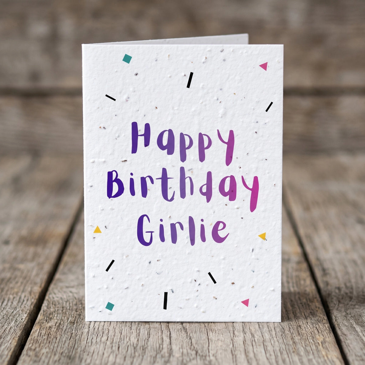 Birthday card with 'Happy Birthday Girlie' text on a wooden surface