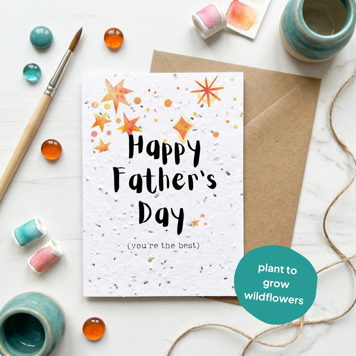 Father's Day card with plantable seeds, surrounded by decorative items on a white surface.