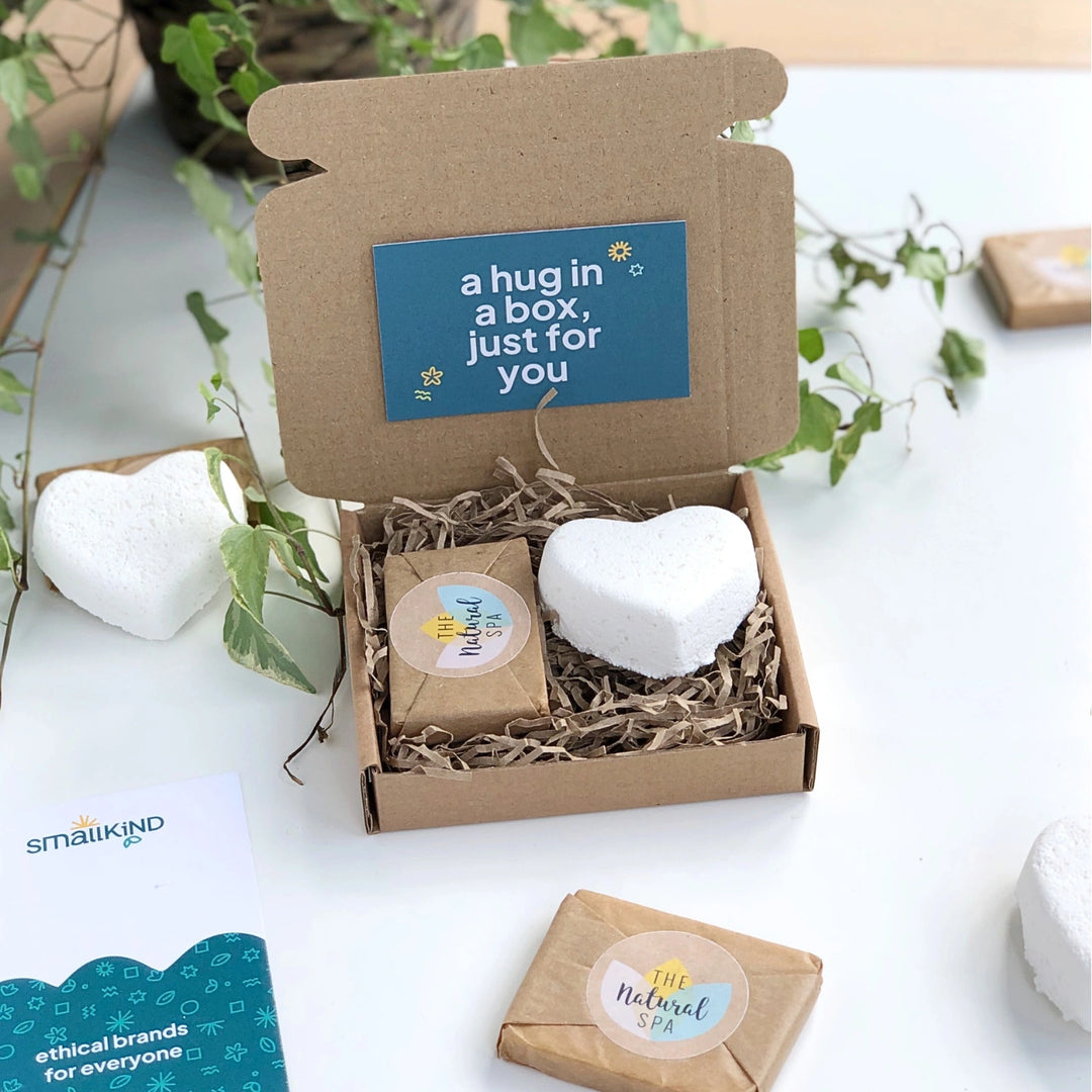 close up of the original smallkind hug in a box gift set which includes a white heart shaped bath bomb and a gift wrapped mini soap