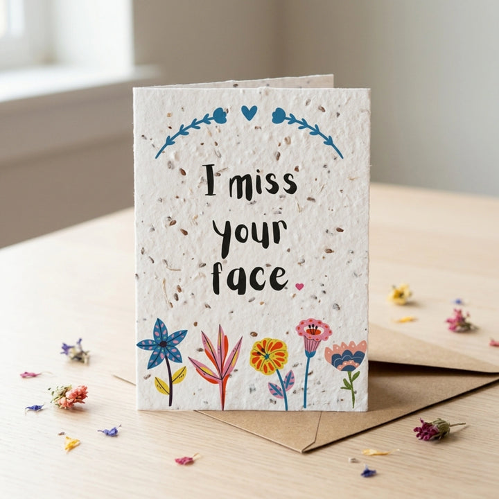 Greeting card with 'I miss your face' text and floral designs on a wooden surface.