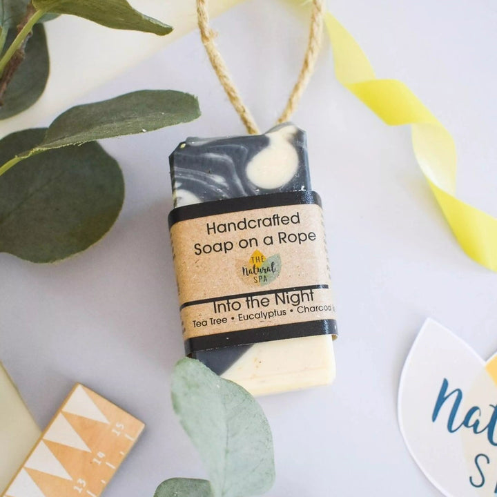 Handcrafted soap on a rope with green leaves and decorative elements on a light background