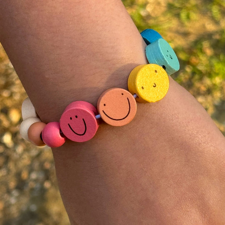 Colourful bracelet with smiley face beads on a wrist against a blurred natural background