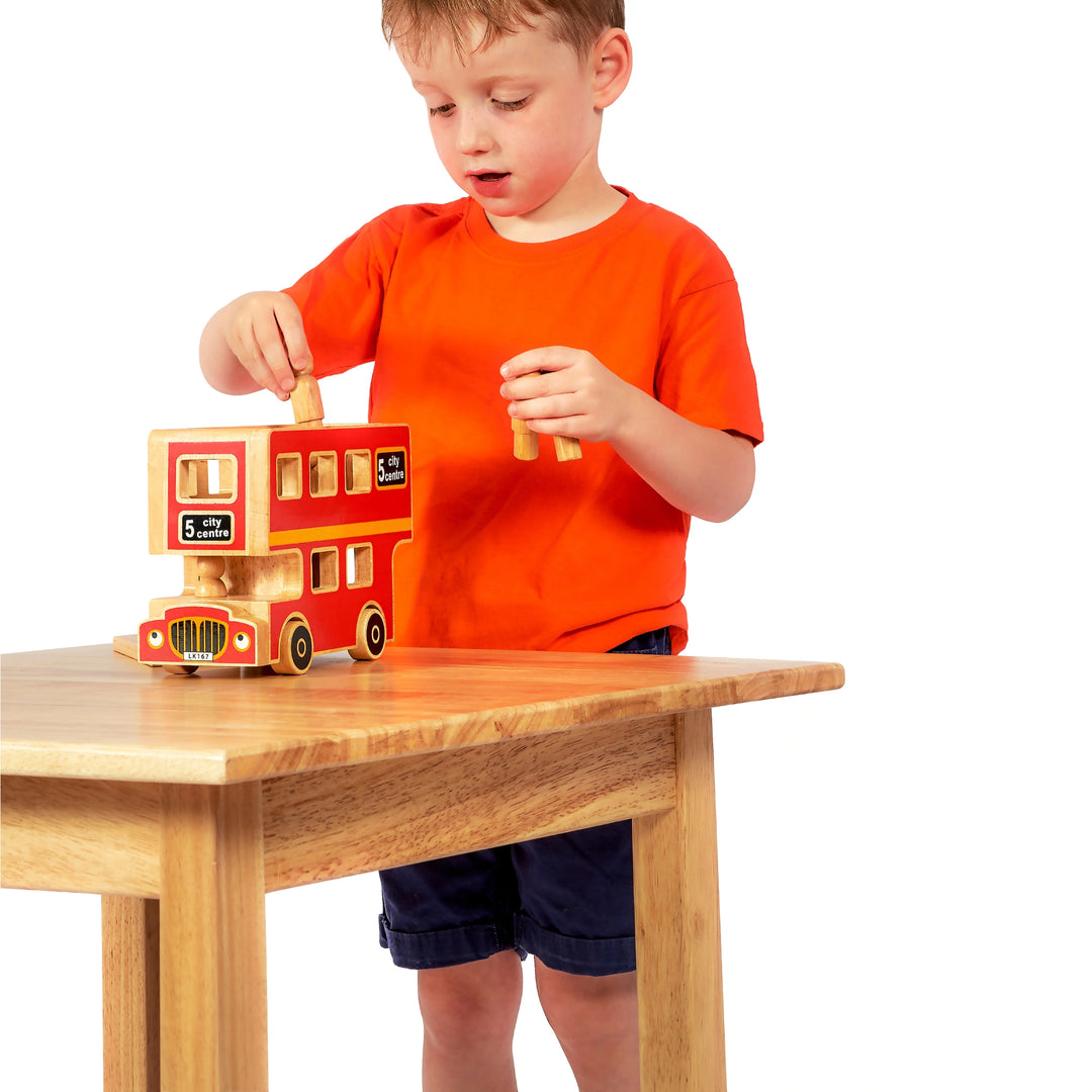 Child playing with a wooden toy bus on a table