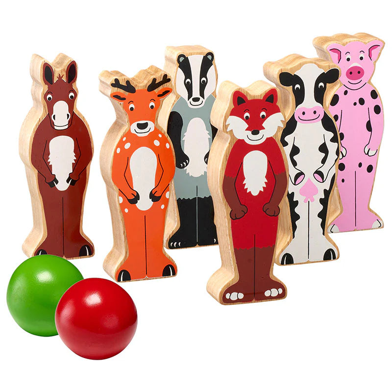 Set of six wooden animal shaped skittles - horse, deer, badger, fox, cow and pig - with two colourful balls on a white background