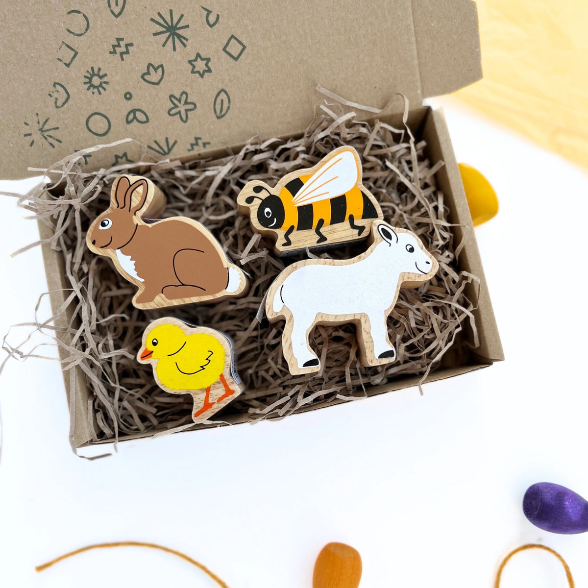 Lanka Kade Spring Animal Play Set in hand-stamped kraft gift box, close-up of wooden rabbit, lamb, chick, and bee figures.