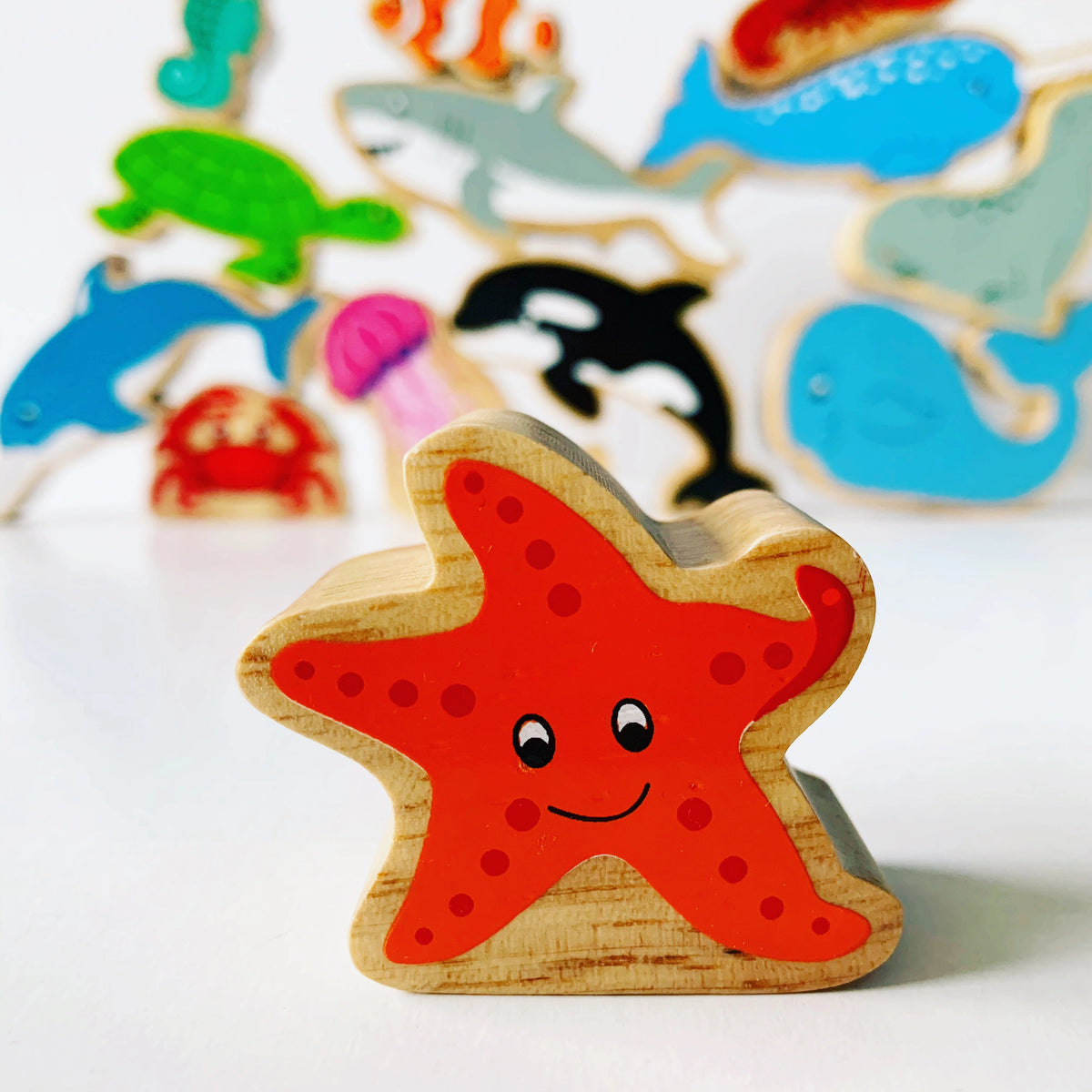 Lanka Kade Wooden Starfish play figure with other sea creatures in the background. For kids age 10 months and over. 