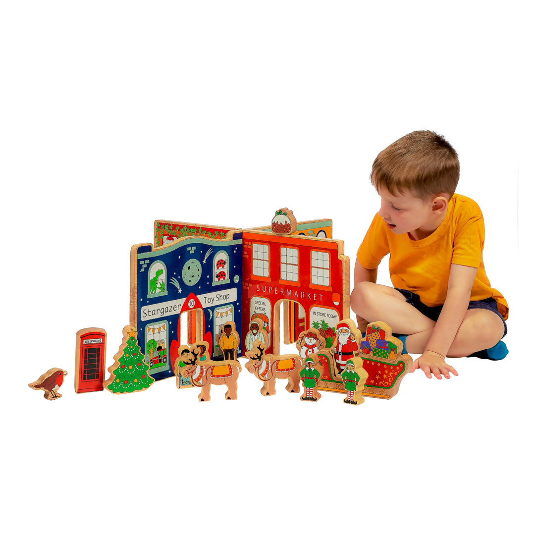 Child playing with a wooden town play scene and wooden characters on a white background