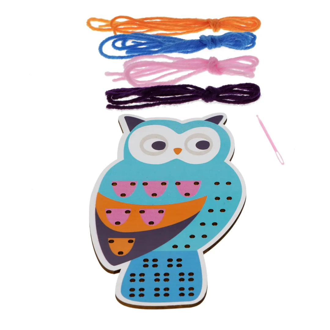 Wooden owl-shaped threading board with colourful strings and a needle on a white background